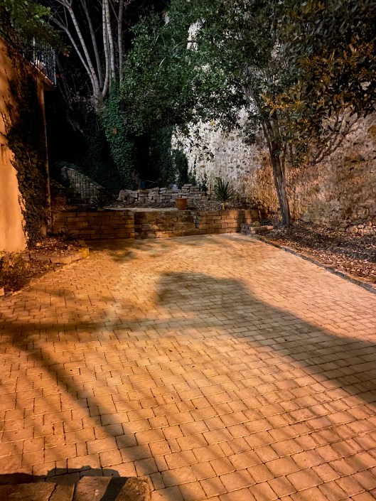 Lövblåst och renspolad stenläggning i kvällsljus